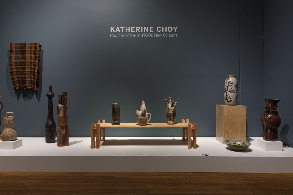Installation view of Katherine Choy exhibiting feature ceramic pieces at a lower eye level, with a couple resting on a table and others on the direct stage of the exhibit.