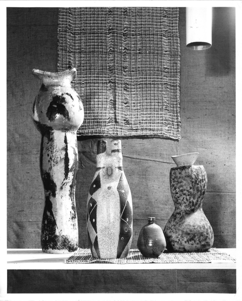 A black and white photograph shows four ceramic works poised on a table.
