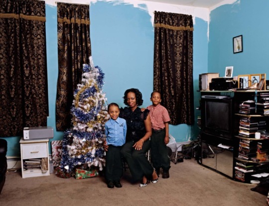 a woman and two small boys smile in a living room with turquoise walls and a christmas tree